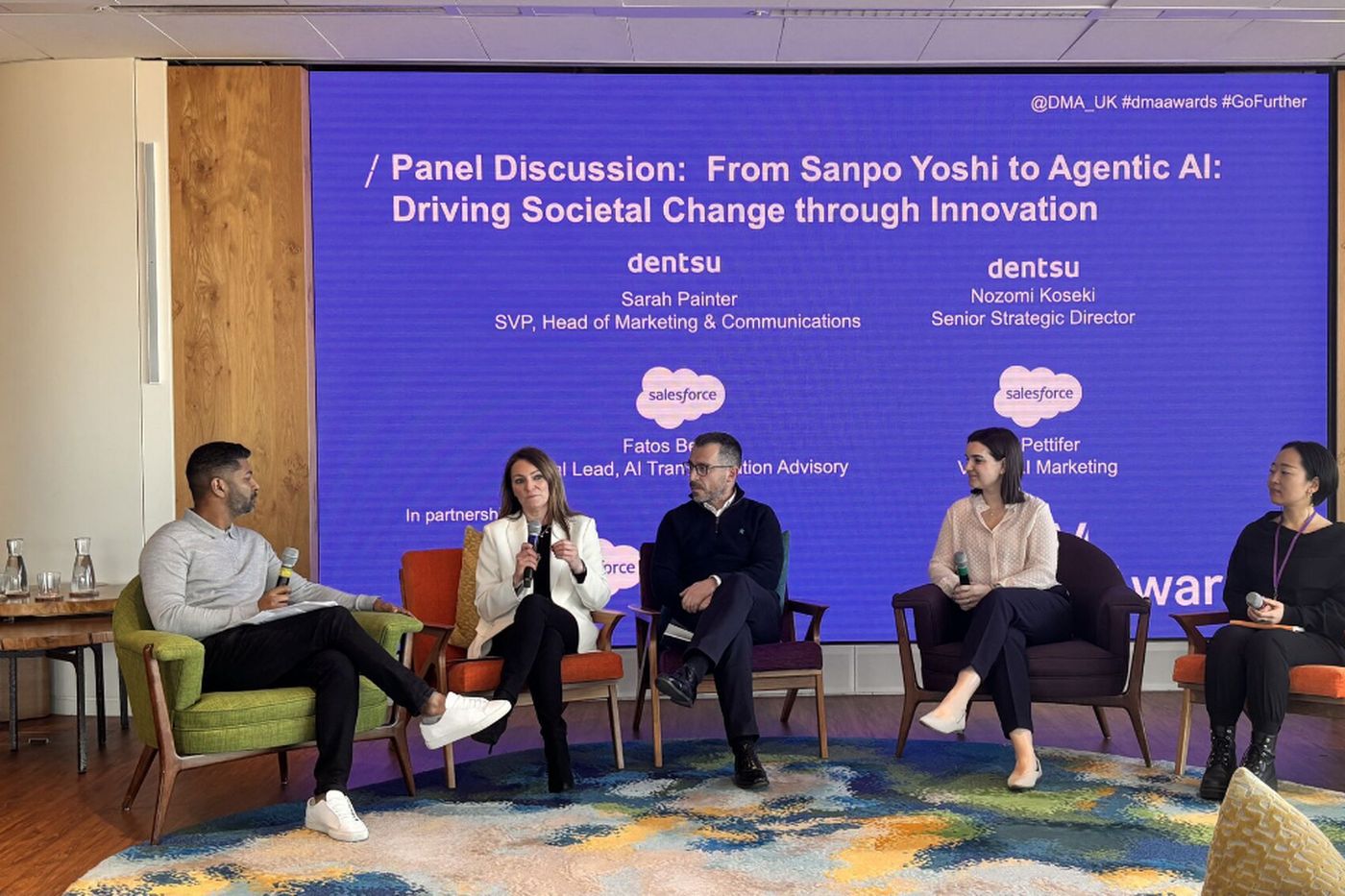 A five-person panel seated in armchairs in front of a screen reading From Sanpo Yoshi to Agentic AI: Driving Societal Change through Innovation.